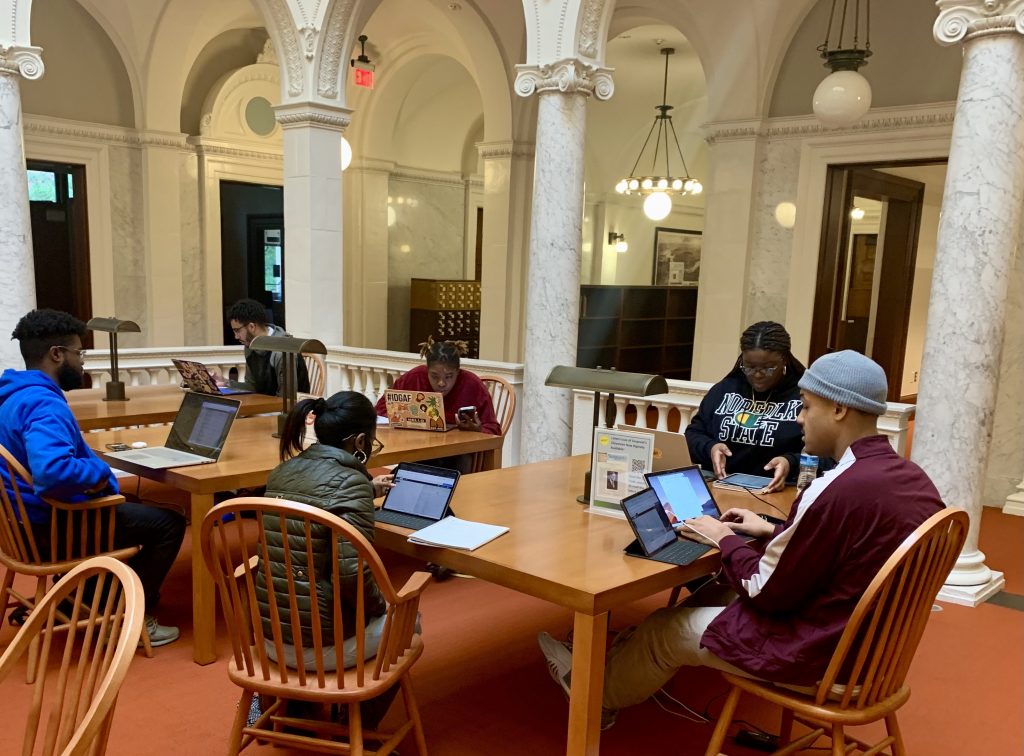 Students sitting at a library table with laptops