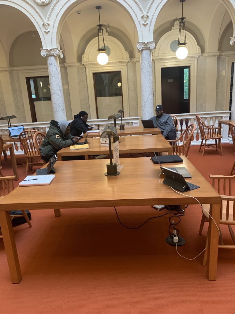 Students working at library tables on laptops